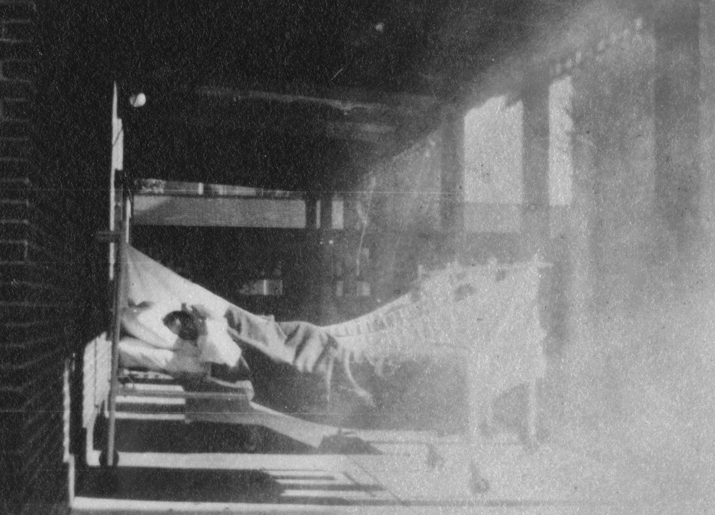 Hospital patient in a wheeled bed outside on a covered porch.