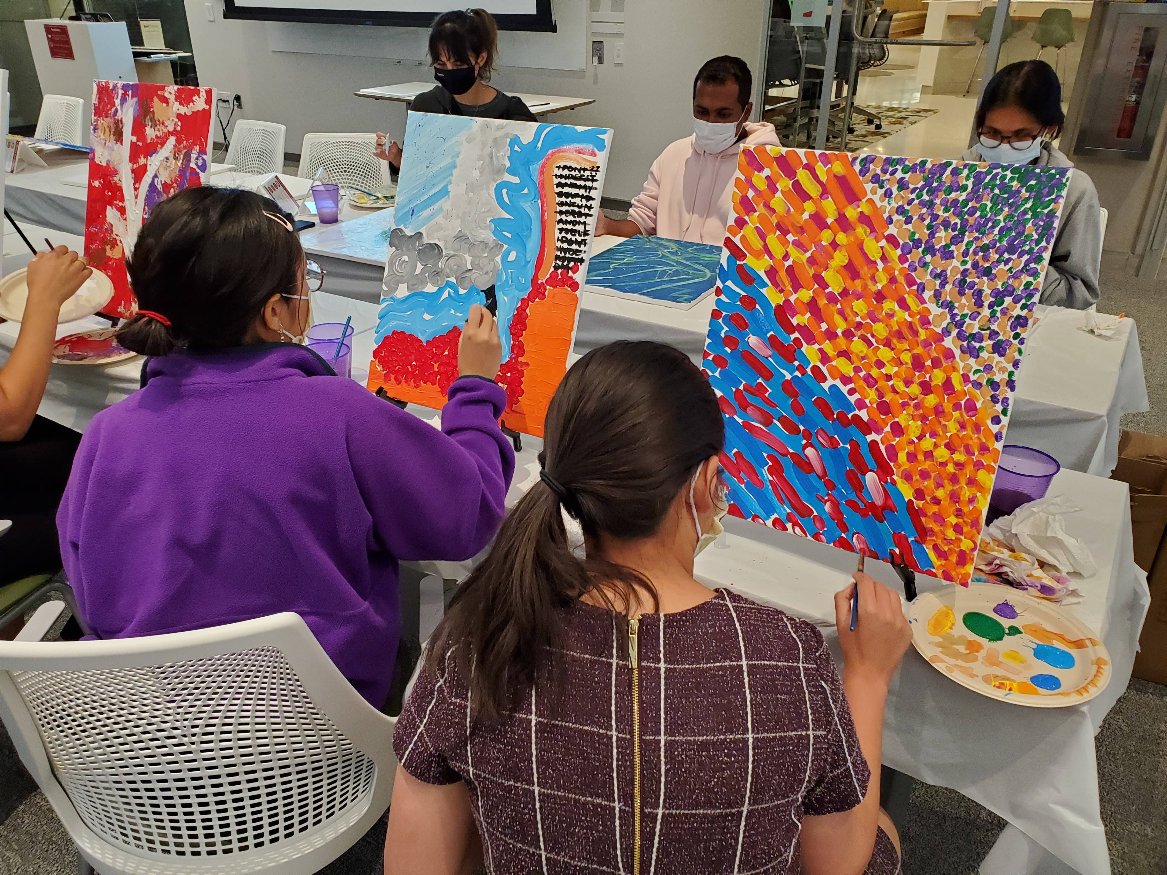 Students painting bright, abstract designs on canvas in a Countway classroom.