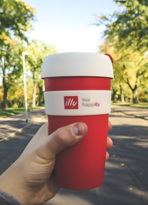 Hand holding a cup of Illy coffee outside
