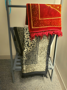 Photo of prayer rugs draped over a shoe rack