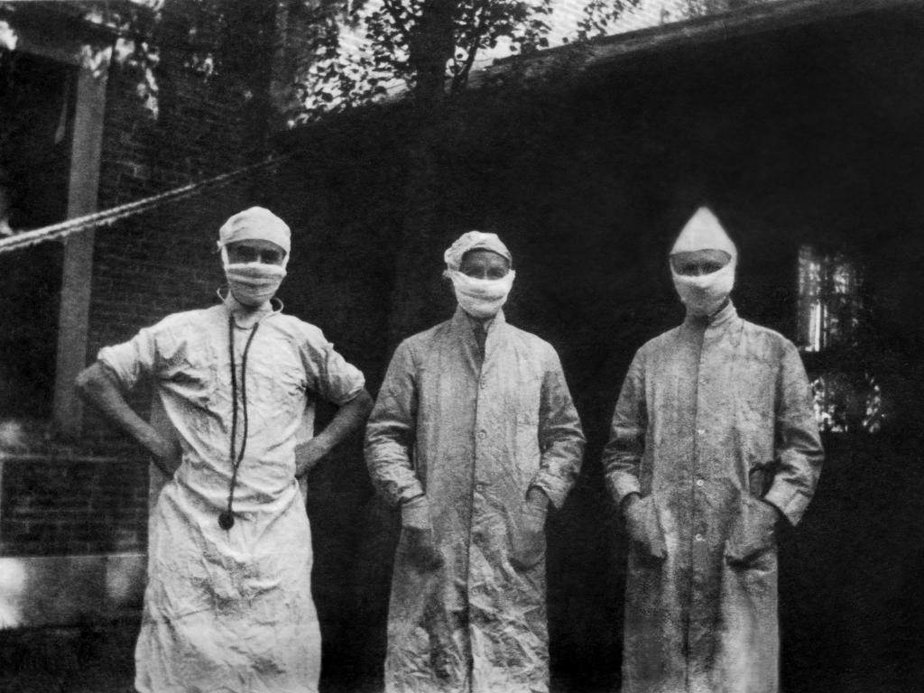 Three doctors wearing overcoats, hats, and face masks