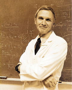 Richard J. Kitz posing in a white coat in front of a blackboard.
