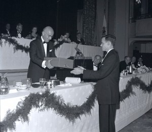 PBBH President Steinert hands a box to J. Linzee Coolidge across a banquet table while seated attendees look on.