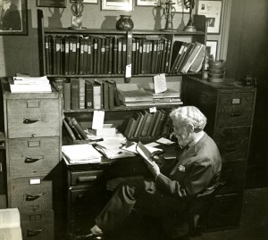 Dickinson writing at an office desk.