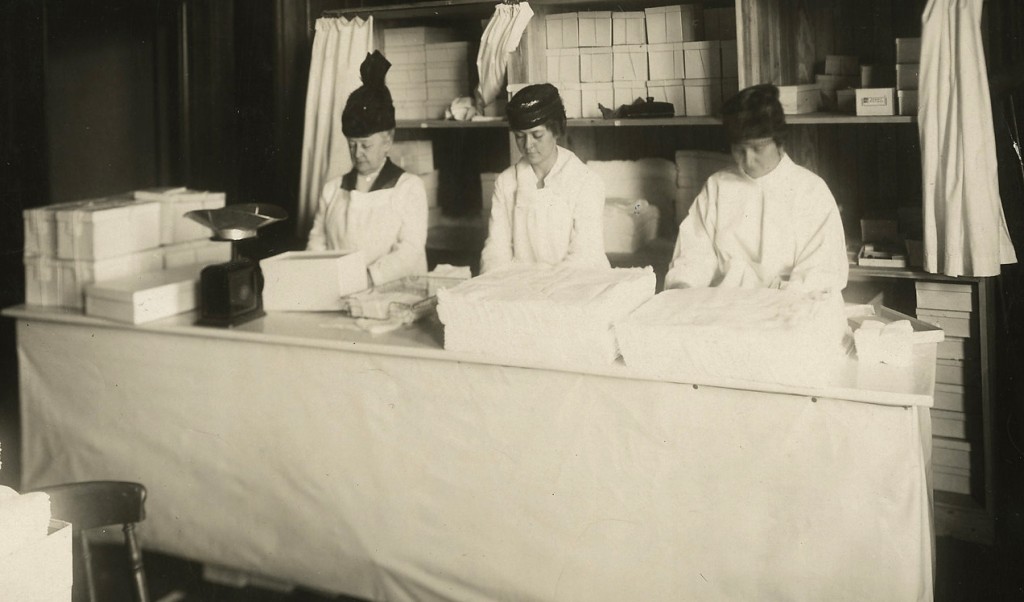 Photograph of three women volunteers in the home work department of the New England Surgical Dressings Committee workrooms.