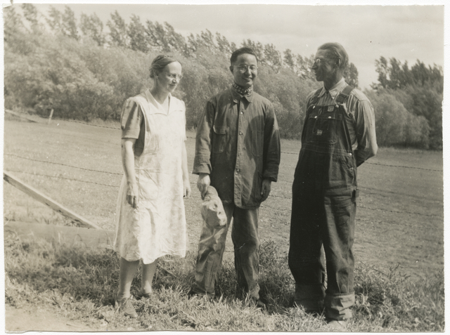 The Benitts smiling with a guest in a field surrounded by trees.