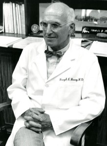 Joseph Murray wearing a lab coat and sitting in a chair.