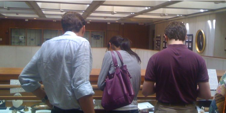 three people looking at a display case of historical artifacts on the 5th floor of Countway Library