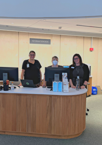 Photo of three staff members standing behind the Info Desk