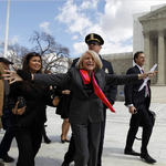 Edith Windsor with her arms wide open walking with other people in front of a court house