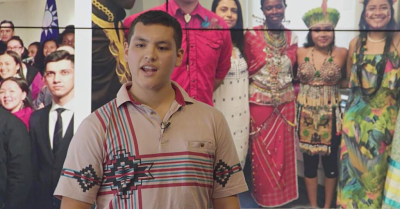 Photo of Victor Lopez-Carmen giving a Ted Talk in front of a screen showing Indigenous people.