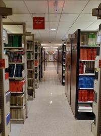 A central hallway in lower level 2 of Countway Library with several rows of bookshelves branching off to the left and right.