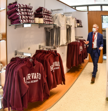 Photograph of HMS Dean Daley walking through the Harvard Coop pop-up store in Countway Library.