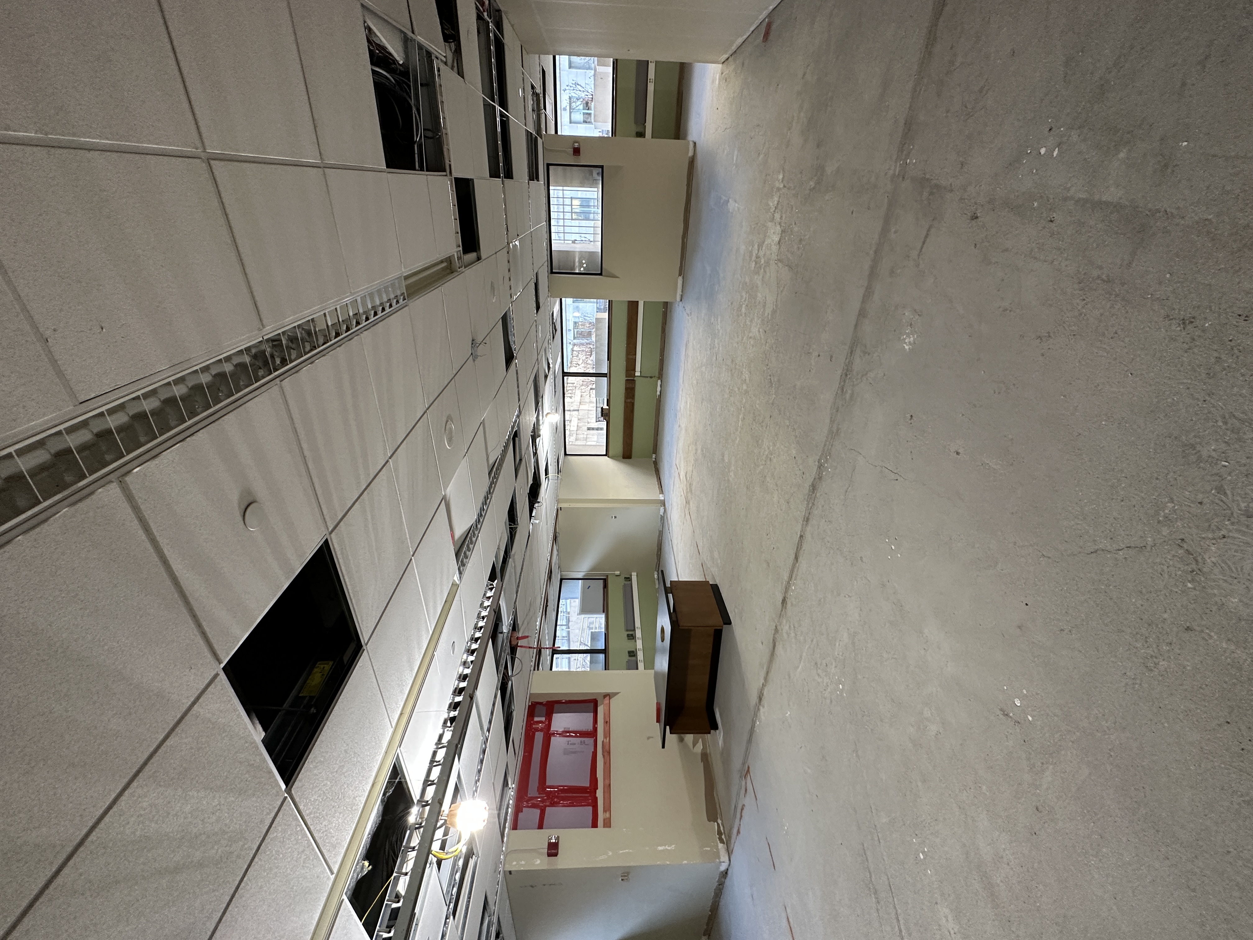 L1 renovation progress showing a cement floor and several missing drop ceiling tiles.