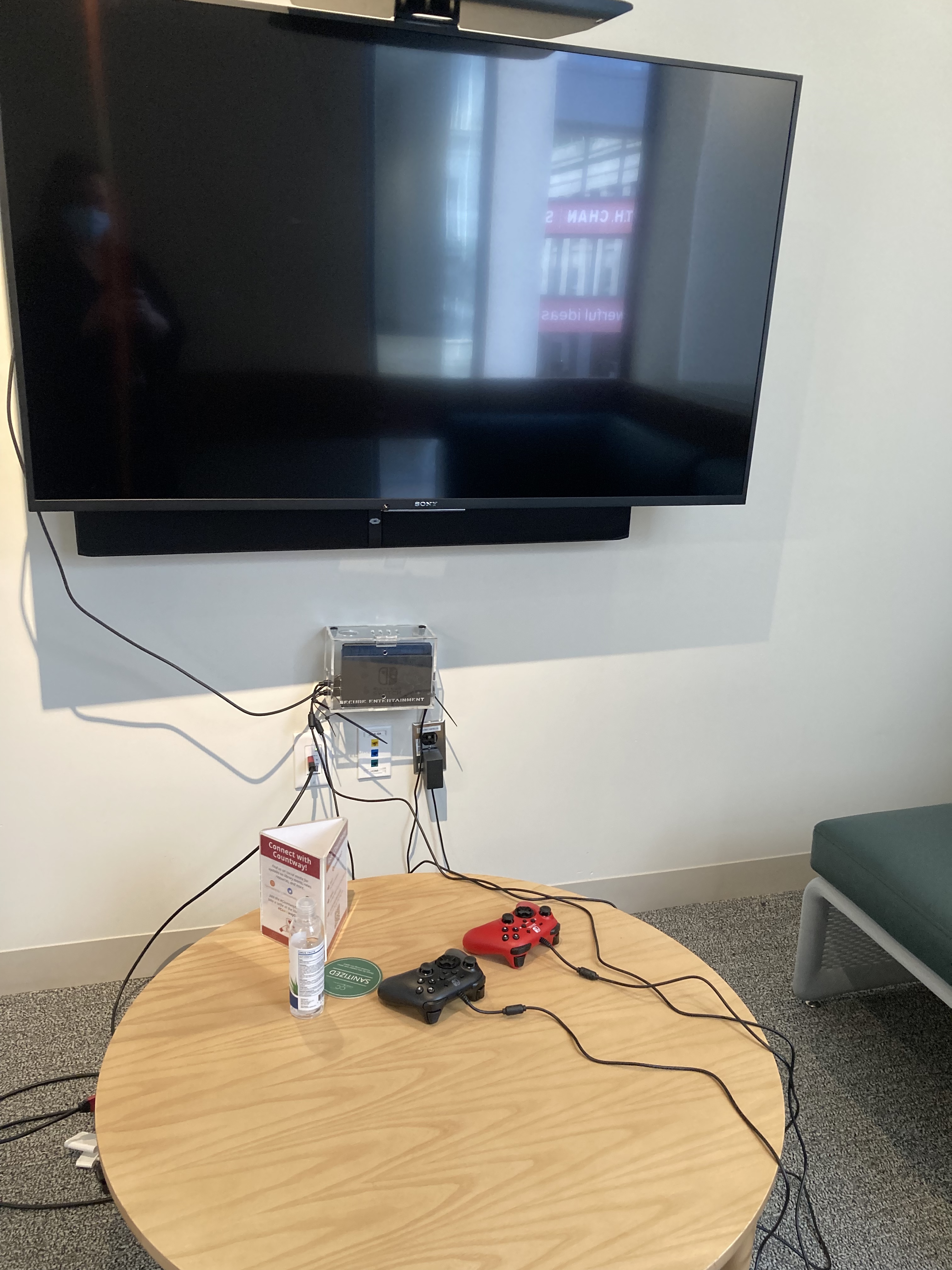 Wall-mounted flat screen television behind a table with two Nintendo Switch controllers
