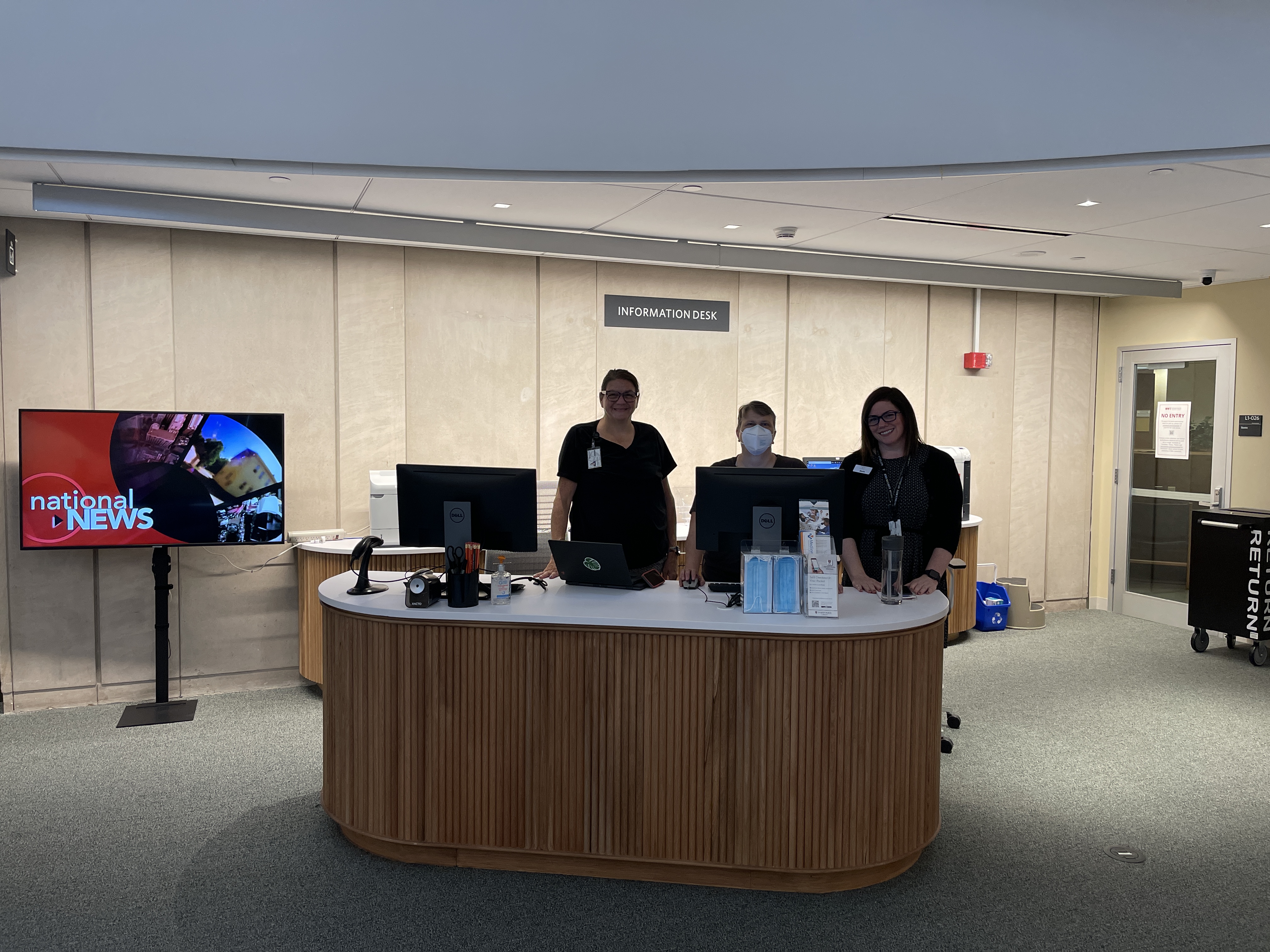 Three staff members standing at the new information desk in Countway Library.