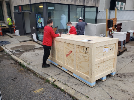 delivery of a large wooden crate marked fragile outside of Countway Library