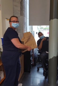 woman receiving books in a paper bag from a security guard.