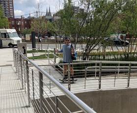 student riding a skateboard on the exterior ramp outside the library