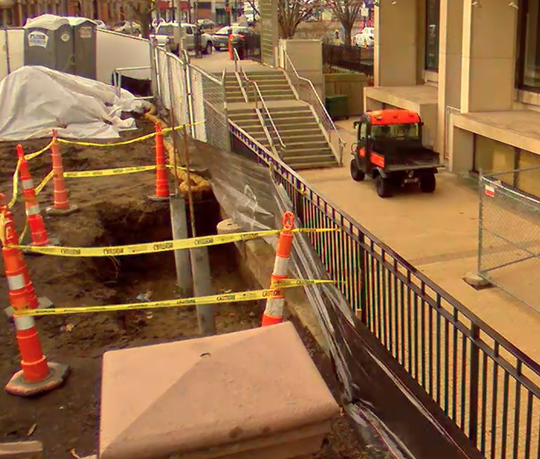 construction cones and caution tape blocking off a pile of dirt outside the library