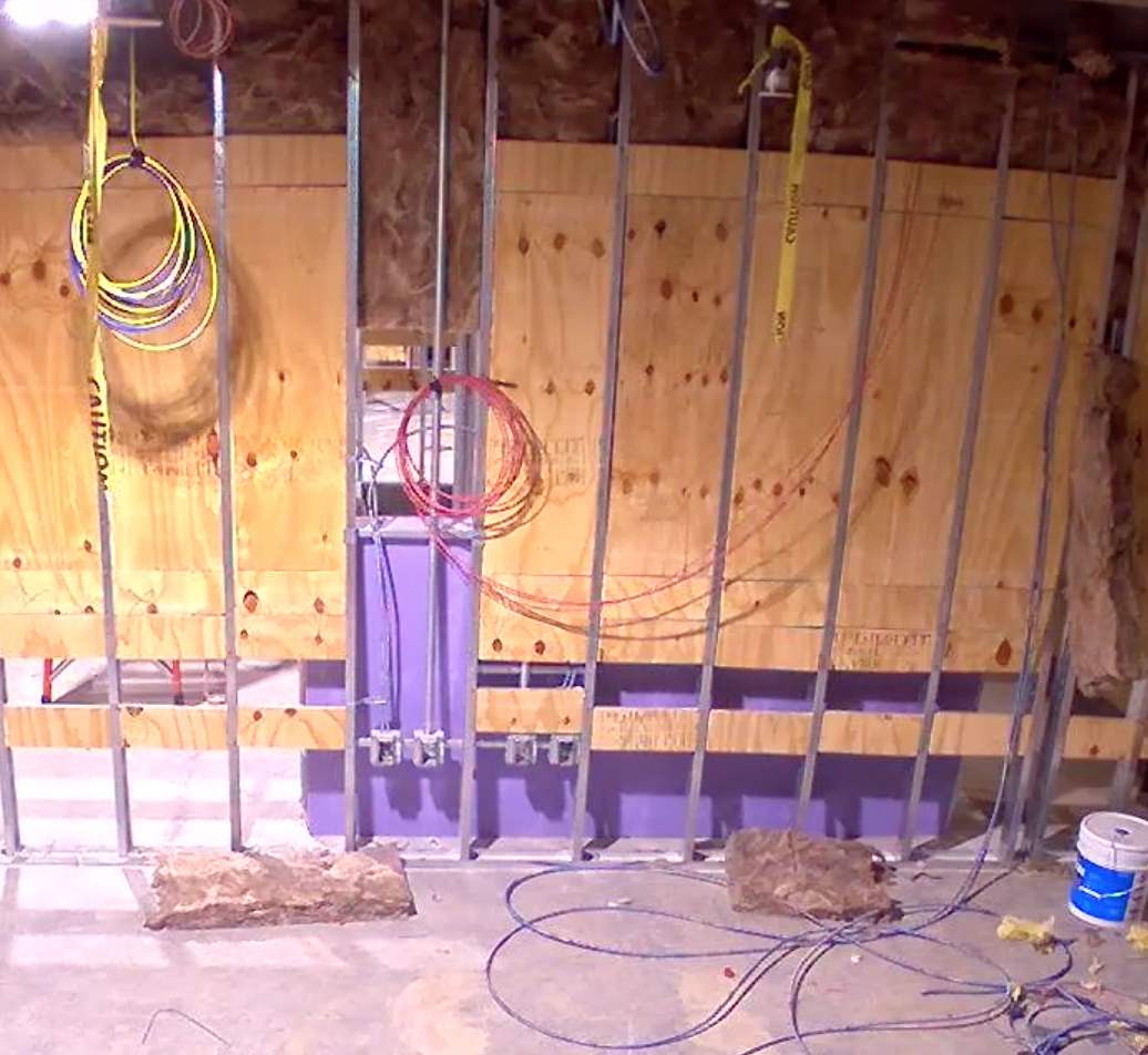 drywall with wooden panel and wires hanging from the wall