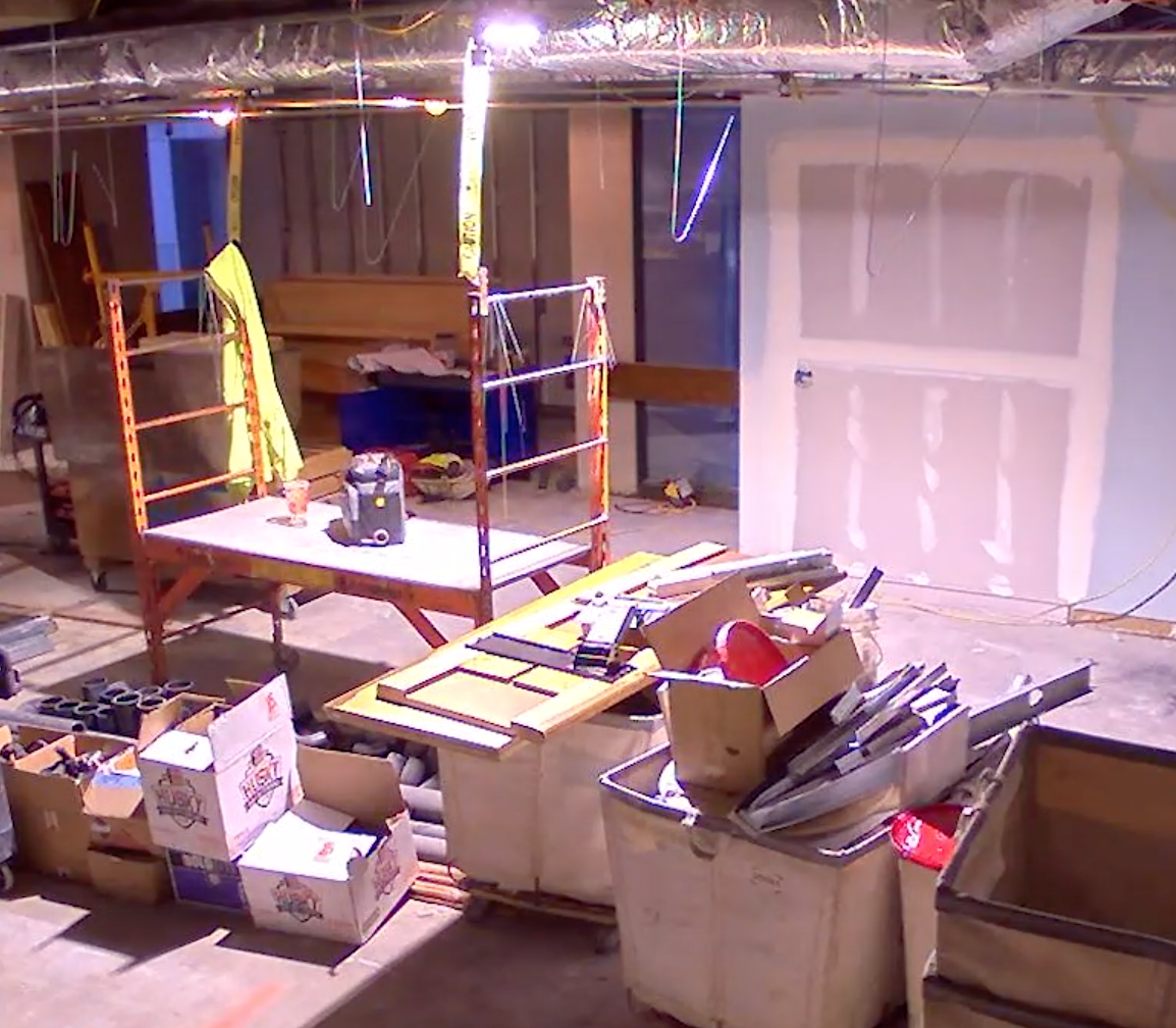 Old reading room with carpet and ceilings removed. Construction materials dispersed throughout the room.