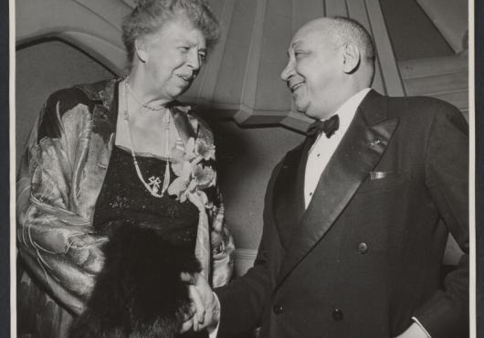 Eleanor Roosevelt (left) and Louis T Wright (right) in evening clothes shaking hands.