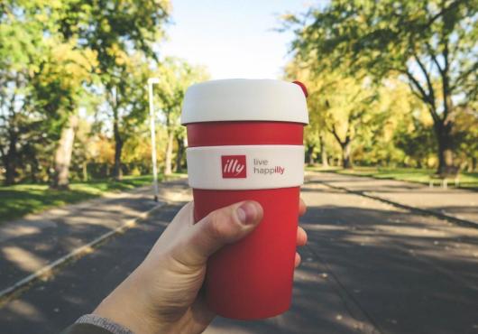 Hand holding a cup of Illy coffee outdoors