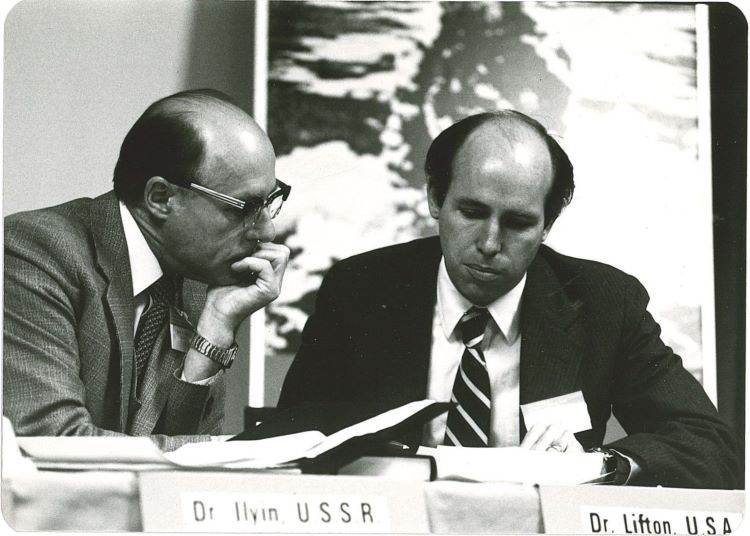 Two men wearing suits and ties looking at papers