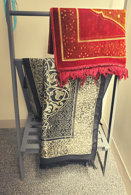 Prayer mats draped over a shoe rack in the Meditation Room