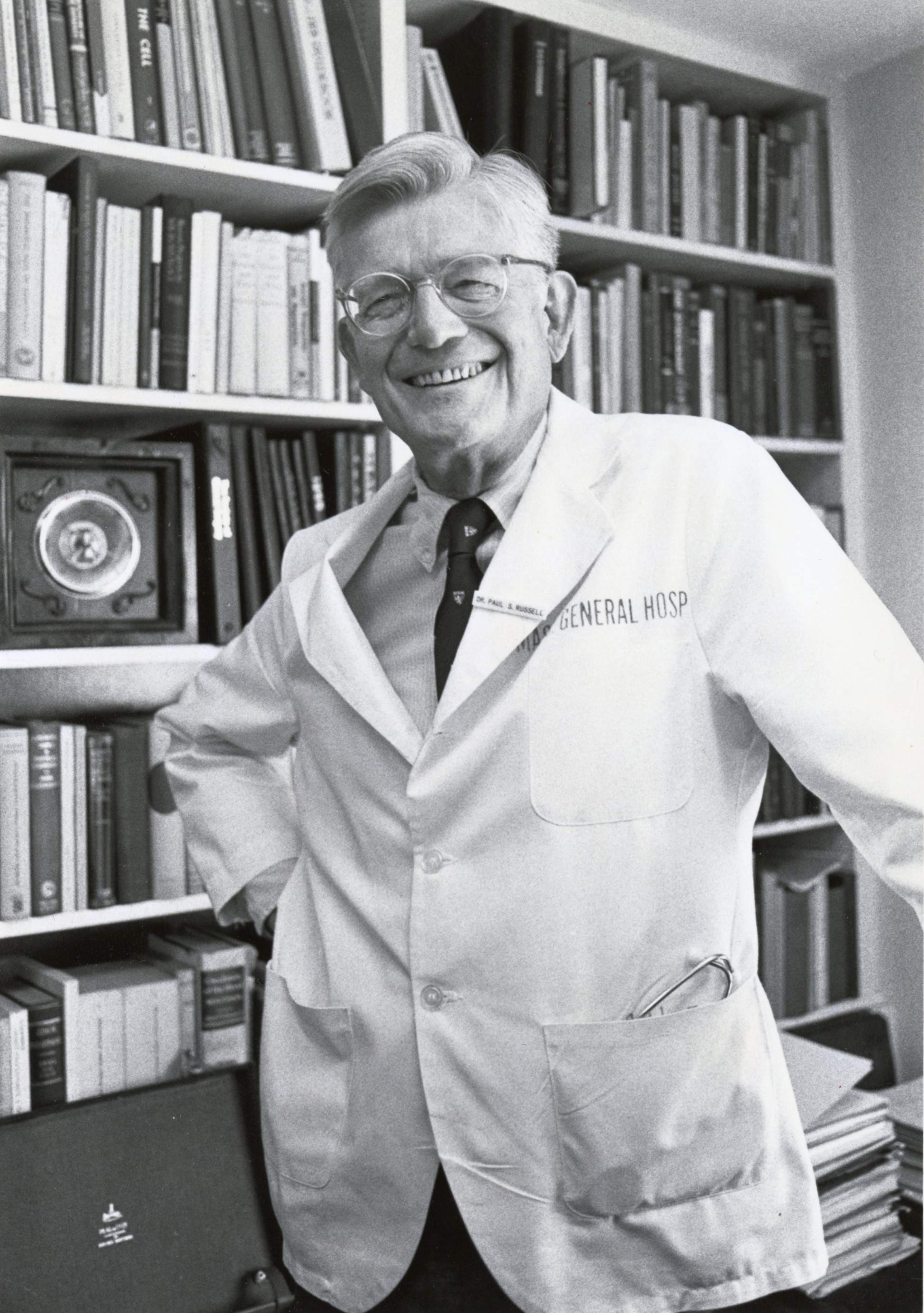 Dr. Paul Russell wearing a physician's coat in front of a bookcase.