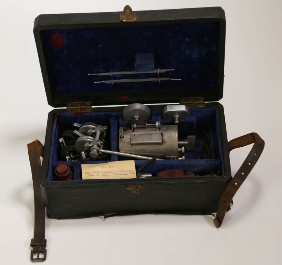 Disassembled Mackenzie Polygraph machine. The case containing the object is open to show the parts.