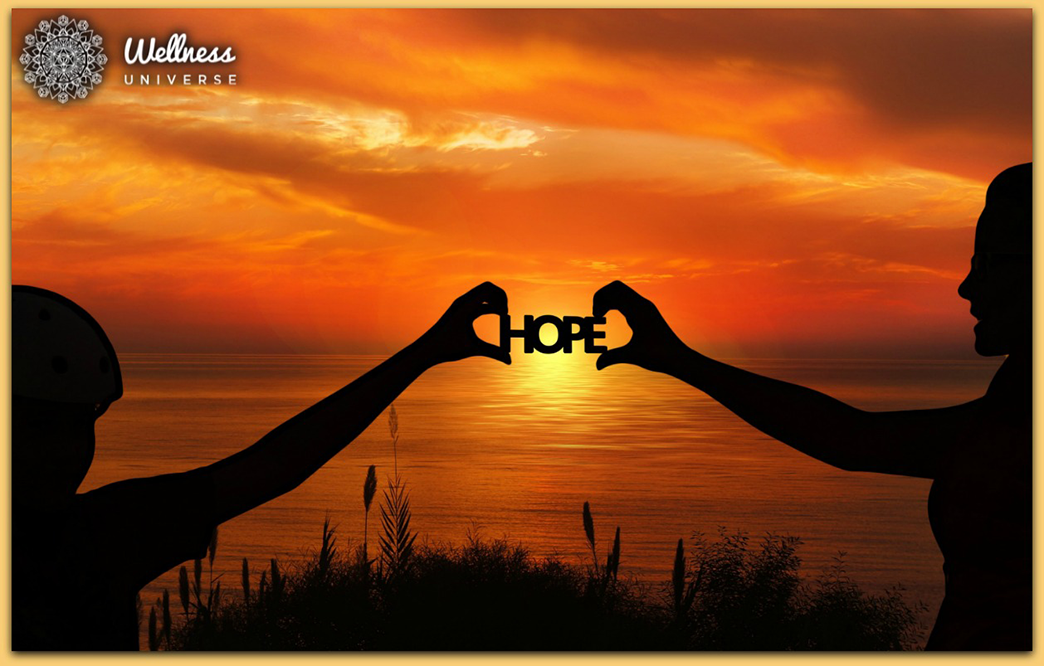 two hands holding up a sign that says "hope" in front of a sunset