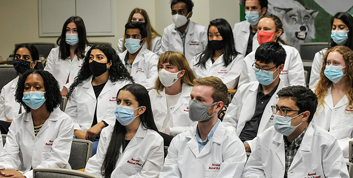 new incoming medical students wearing white coats and masks